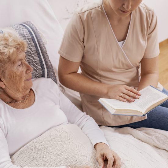 helpful young carer reads a book to an elderly wom 2021 08 27 16 16 33 utc